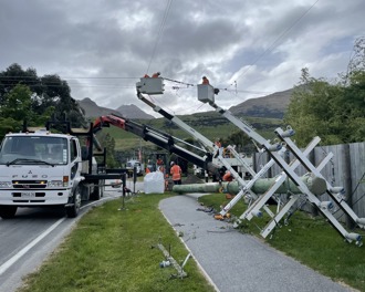 Photo shows a new power pole lying on the ground to be installed next to a truck and two cherry pickers with people in the baskets working.