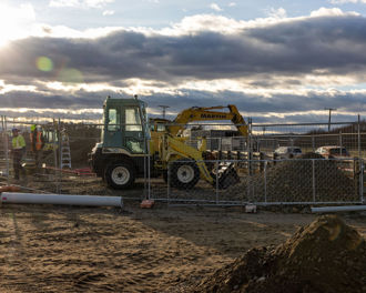 Photo shows construction site with diggers and workers.