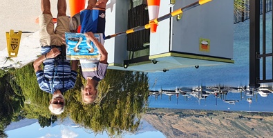 Streetart: Sunny day next to Lake Wakatipu, artist and another person standing in front of a transmission box to be painted. 