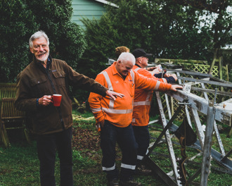 Team of workers having a coffee break on Bellevue Place in Port Chalmers, leaning on part of one of the towers that have been removed