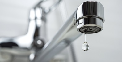 Photo of a drop of water dripping from the tap. Selective focus.