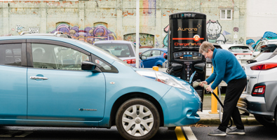 Woman plugging her electric car into an Aurora Energy ChargeNet fast charge station