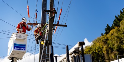 Workers at top of power poles working on the lines