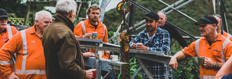 Workers standing at the base of a power line having a coffee break