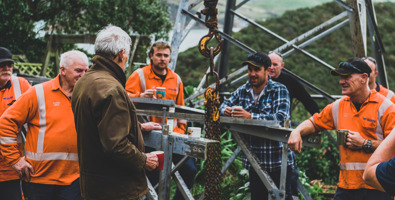 Workers standing at the base of a power line having a coffee break