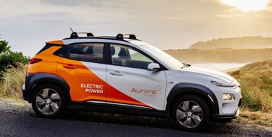 Photo of Aurora Energy branded electric car with the sun setting in the background.