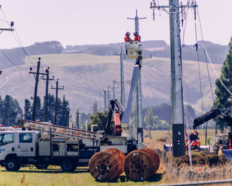 Workers in an elevated working platform working on power lines on the poles